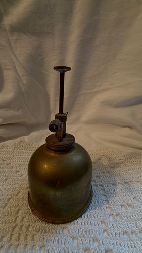 Vintage brass hand pump oiler with curved spout and long handle, made in USA, on white textured fabric background.
