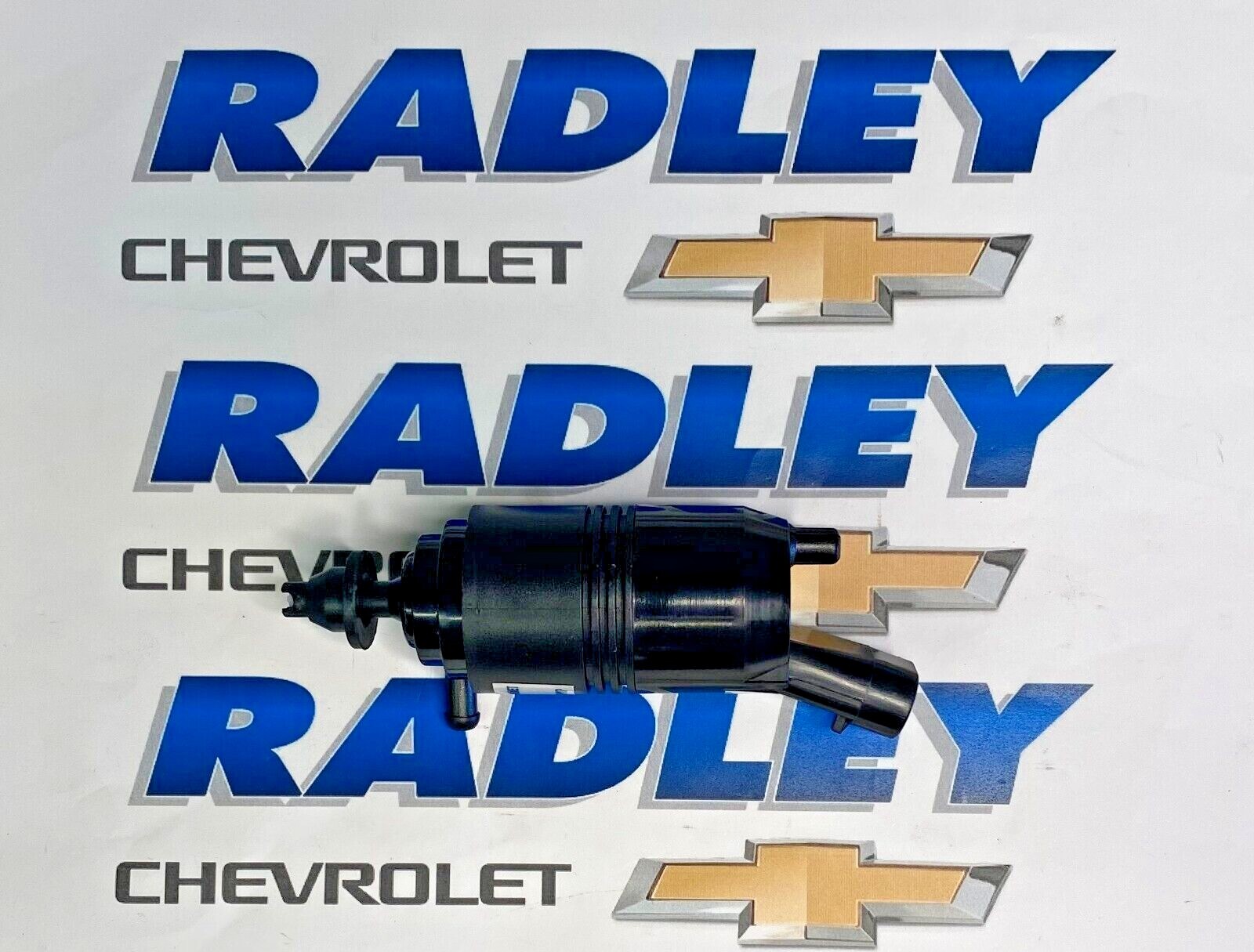 White GM OEM windshield washer pump with black housing, surrounded by blue “RADLEY CHEVROLET” text and logo.