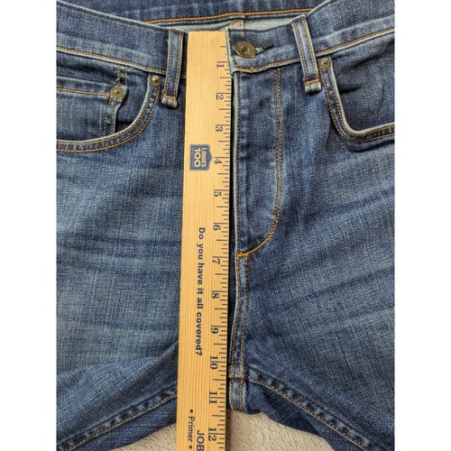 Blue denim Rag & Bone Fit 2 slim jeans with faded thighs, five-pocket design, and orange stitching, measured by inch ruler.