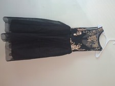 Black sleeveless party dress has a golden floral pattern on the front 