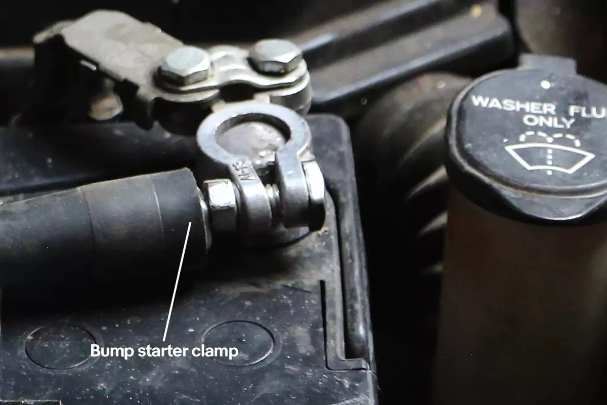 A bump starter clamp attached to the positive battery post of a vehicle.