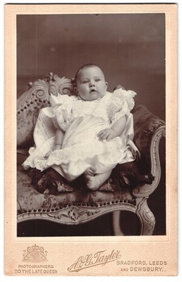 Fotografie A. & G. Taylor, Bradford, Portrait süßes Baby im weißen Kleid mit na 