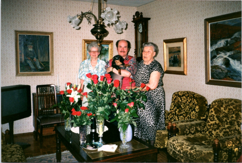 lata 90. znalezione zdjęcie Finlandia - mężczyzna trzyma psa z kobietami po kwiatach przyjęcie urodzinowe - Zdjęcie 1 z 2