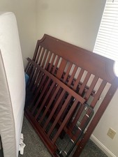 Brown gently used crib with open but new mattress, screws included