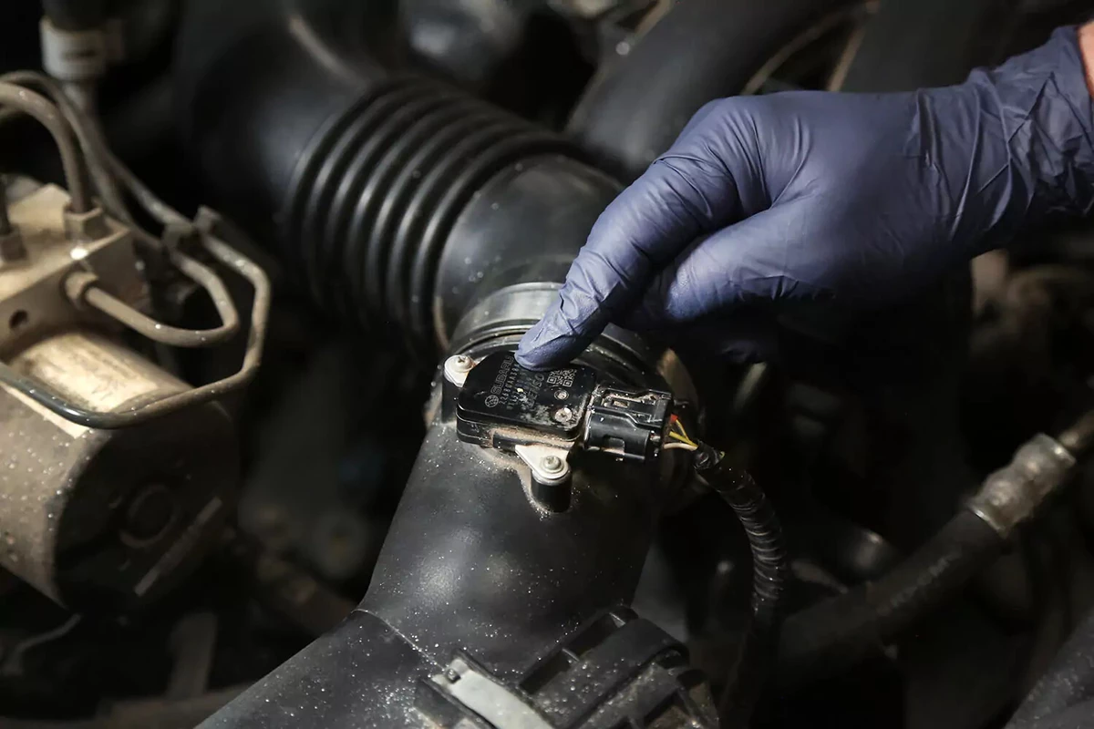 Finger pointing to an MAF sensor in an engine.