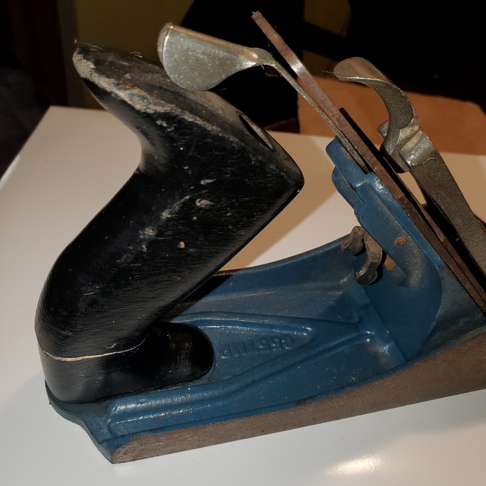 Teal blackhawk C557MP wood hand plane with worn silver handle, flat rectangular base, and engraved oval shape on side.