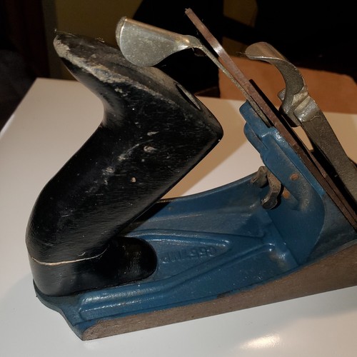 Teal blackhawk C557MP wood hand plane with worn silver handle, flat rectangular base, and engraved oval shape on side.