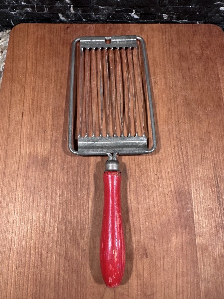 A charming vintage Holland-made combo slicer with a warm redwood handle that does tomatoes, eggs, AND cheese — a retro kitchen multi-tool that looks as good as it functions.