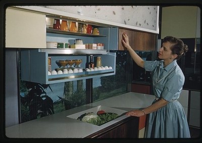 Photo:1960s Modern Kitchen Woman Opening Cabinets Interior Design