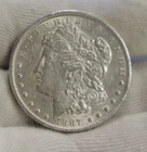 1887 O  US Morgan Dollar $1 AU (Cleaned, Rim Nick)
