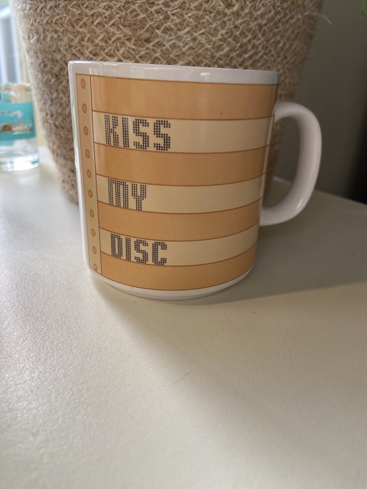 'Kiss My Disc' on a vintage ceramic mug is the peak of 80s office nerd humor — genuinely funny, collectible, and impossible to find.