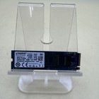Black Kingston M.2 NVMe SSD with blue chip, white label, and gold accents on clear stand.