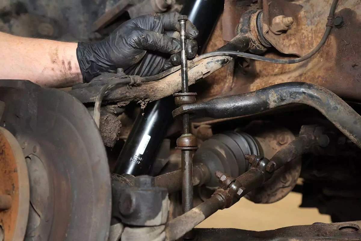 A mechanic removes the bolt out from the end link assembly.