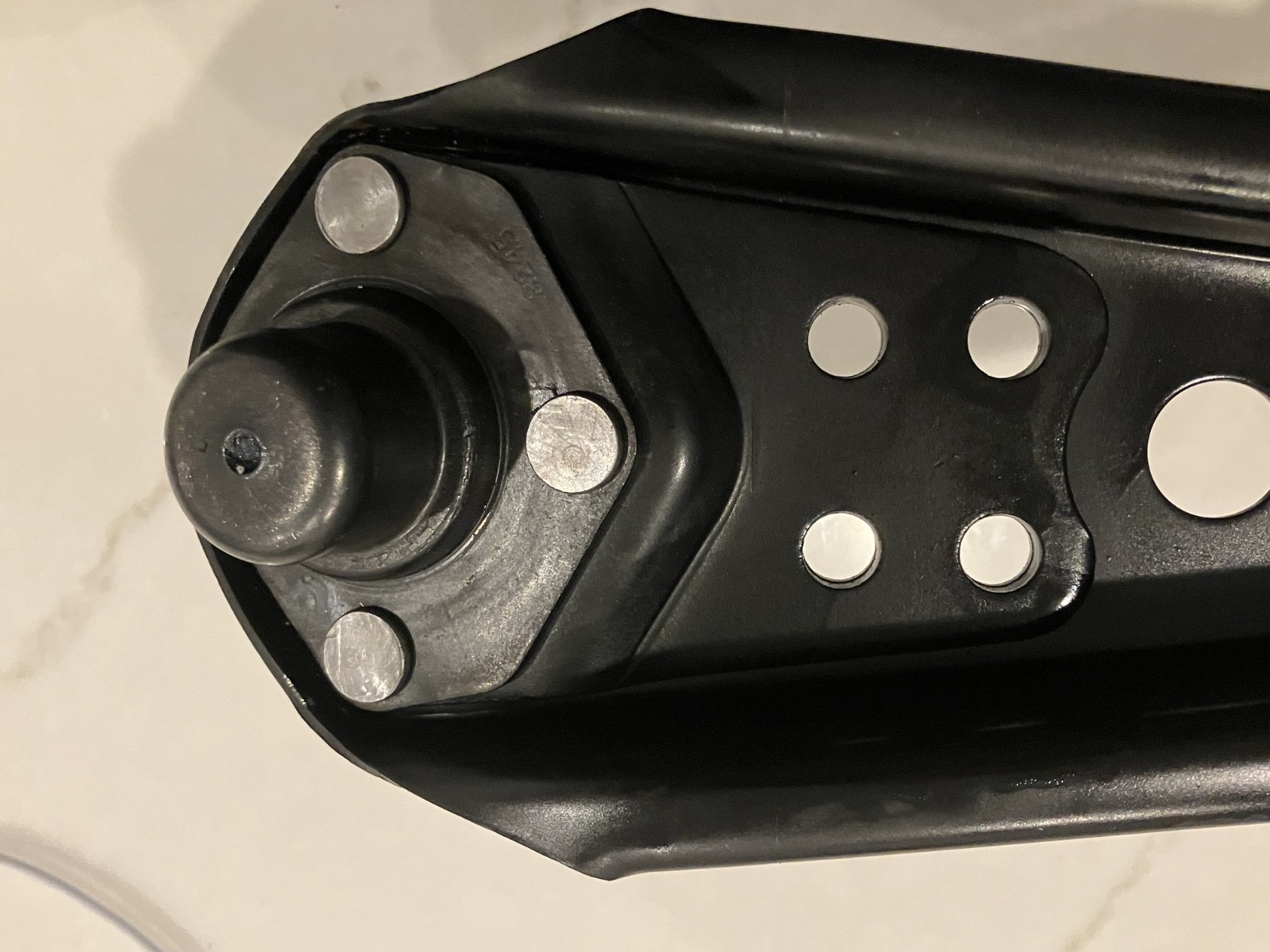 Black lower control arms with silver mounting holes and black rubber O-rings on a 1967 Ford Mustang.