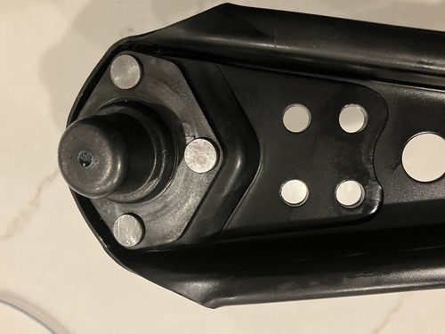 Black lower control arms with silver mounting holes and black rubber O-rings on a 1967 Ford Mustang.