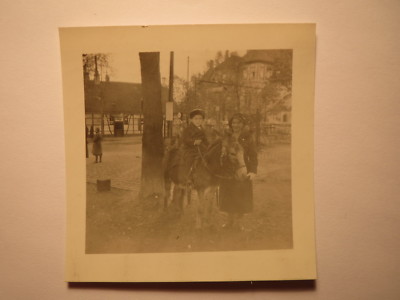 Boy sitting on a donkey next to a young woman on the street / photo