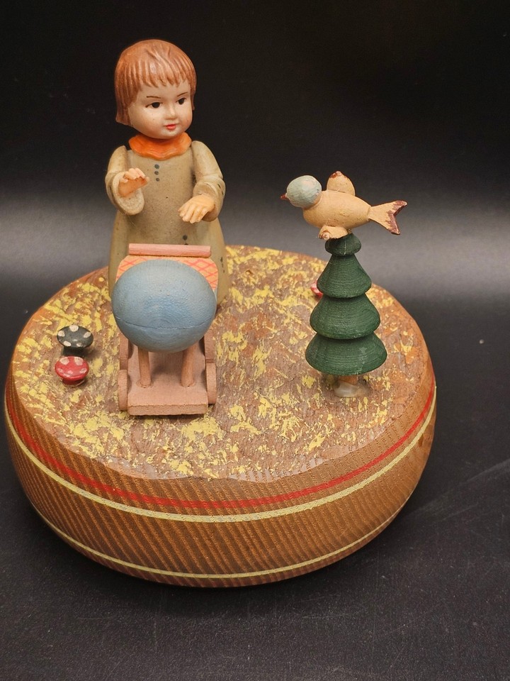 A Reuge Swiss wind-up music box with a carved wooden girl-in-cradle scene playing Brahms Lullaby — deeply sentimental and genuinely well-made.
