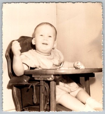 Vtg B&W Snapshot Happy Baby In Wooden High Chair Eating Smiling Infant 1950s