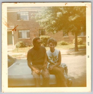 Vtg Color Snapshot Couple Sitting On Vintage Car Hood Brick Building Yard 1969