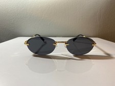 Unisex, rimless, oval shaped sunglasses with black lenses and gold frame