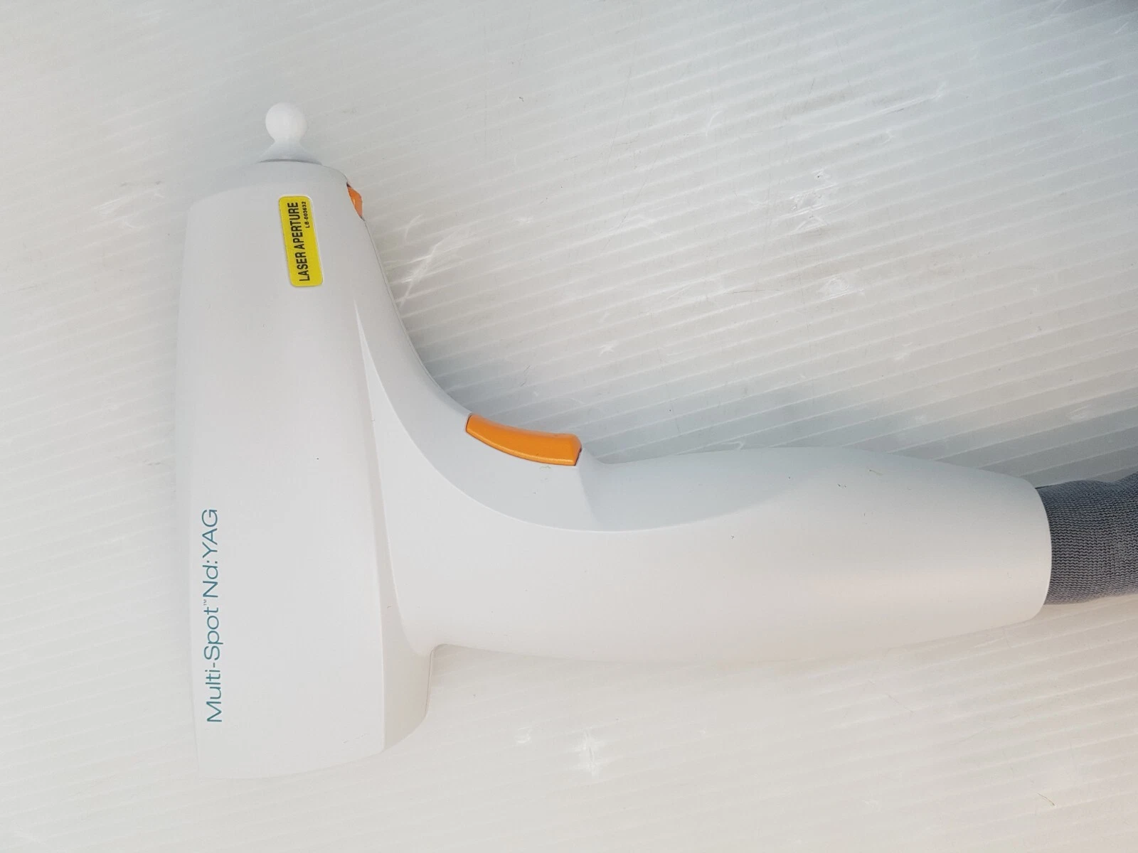 Side of the white Multi-Spot Nd:YAG handpiece with laser aperture label