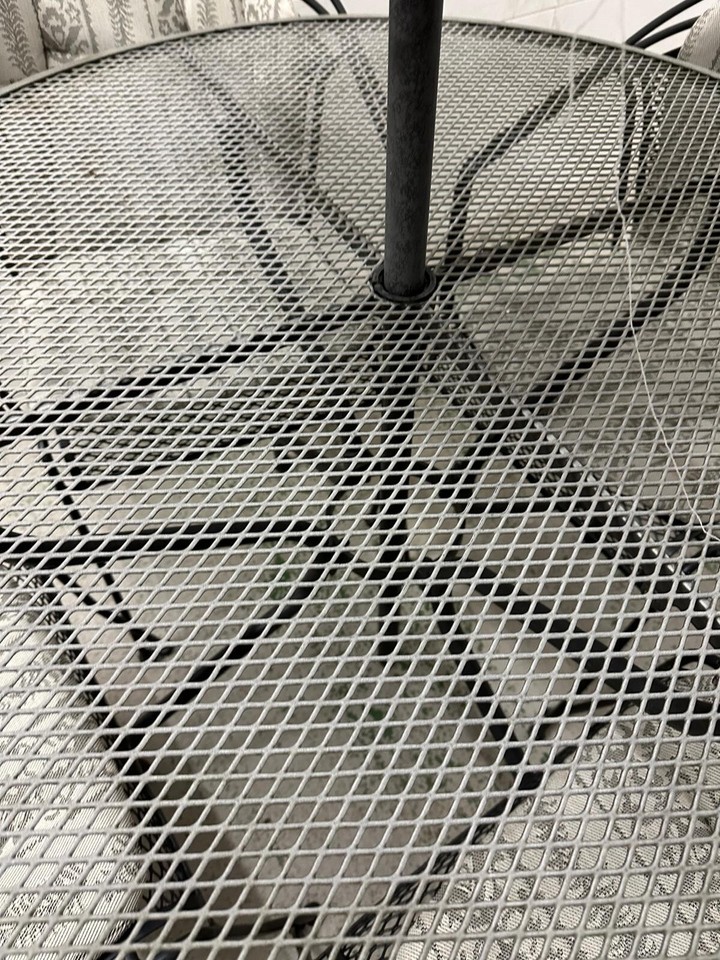 black metal garden table and four chairs with cushions and a central