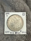 KEY 1892-S MORGAN SILVER DOLLAR. AU with rim nicks. Muted luster. Light toning.