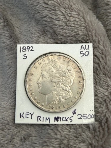KEY 1892-S MORGAN SILVER DOLLAR. AU with rim nicks. Muted luster. Light toning.