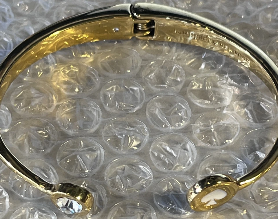 Brazalete Kate Spade New York dorado con bisagras con pala blanca y estrás transparente Foto 2 de 4