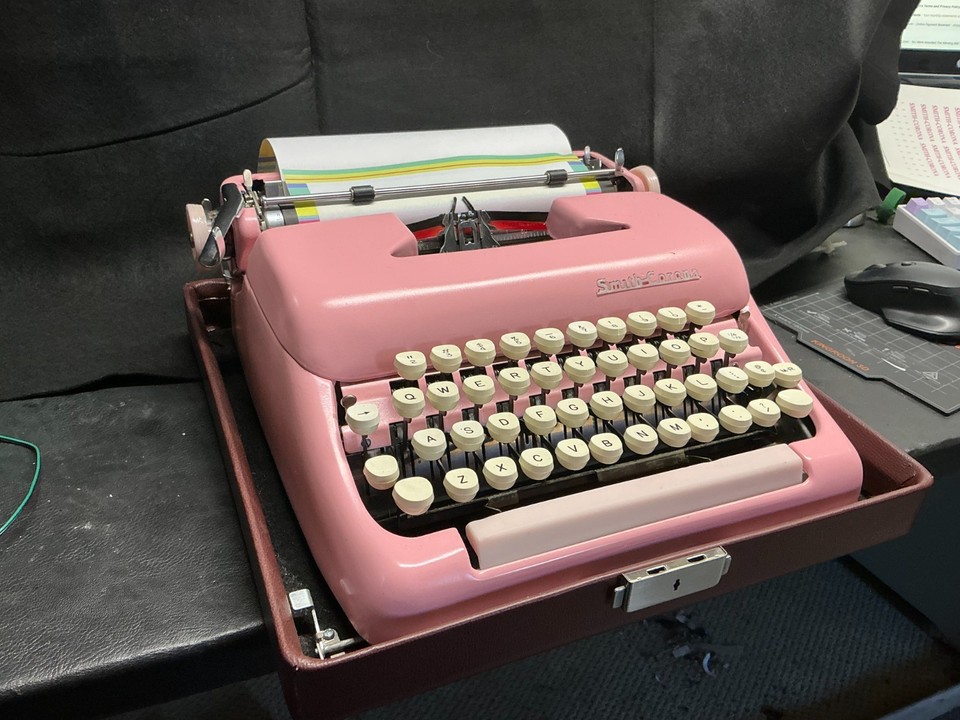 Bubblegum-pink 1950s Smith Corona Clipper — the color alone makes it a statement piece and instant room focal point.