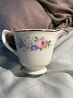 White ceramic pitcher with gold rim, pink rose floral print, and blue text reading “Made in U.S.A.” on the side.