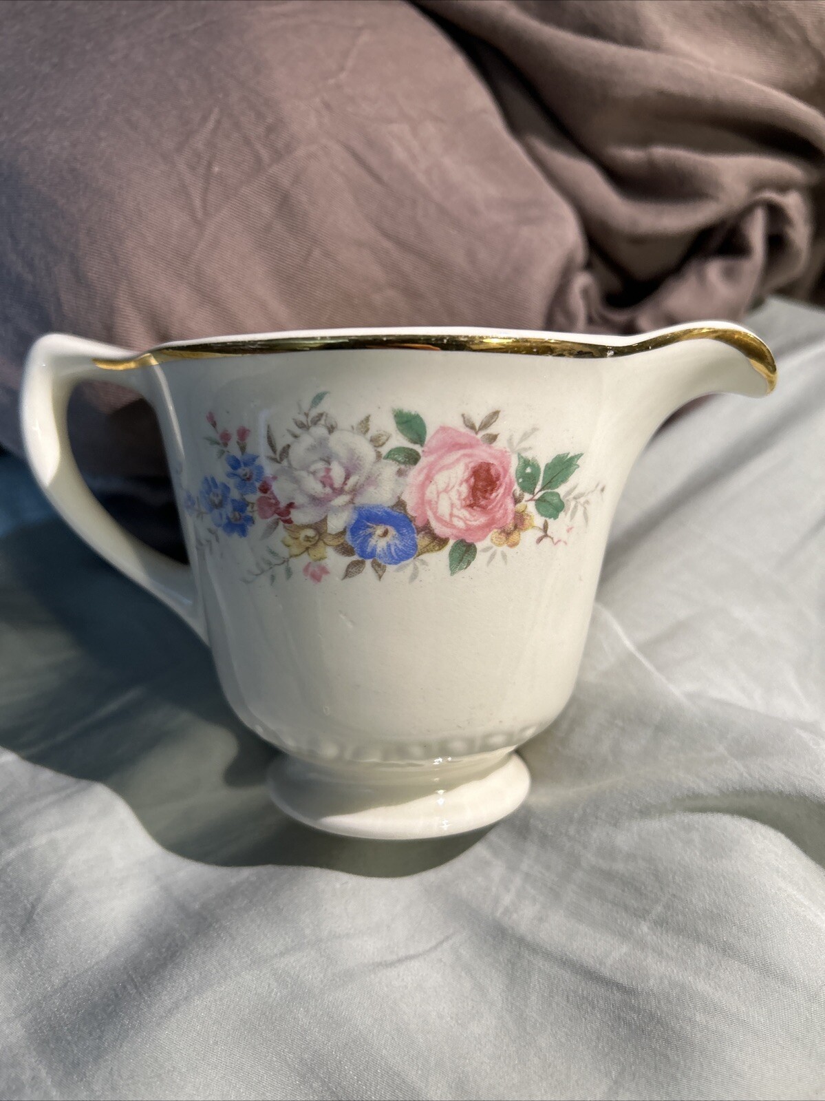 White ceramic pitcher with gold rim, pink rose floral print, and blue text reading “Made in U.S.A.” on the side.