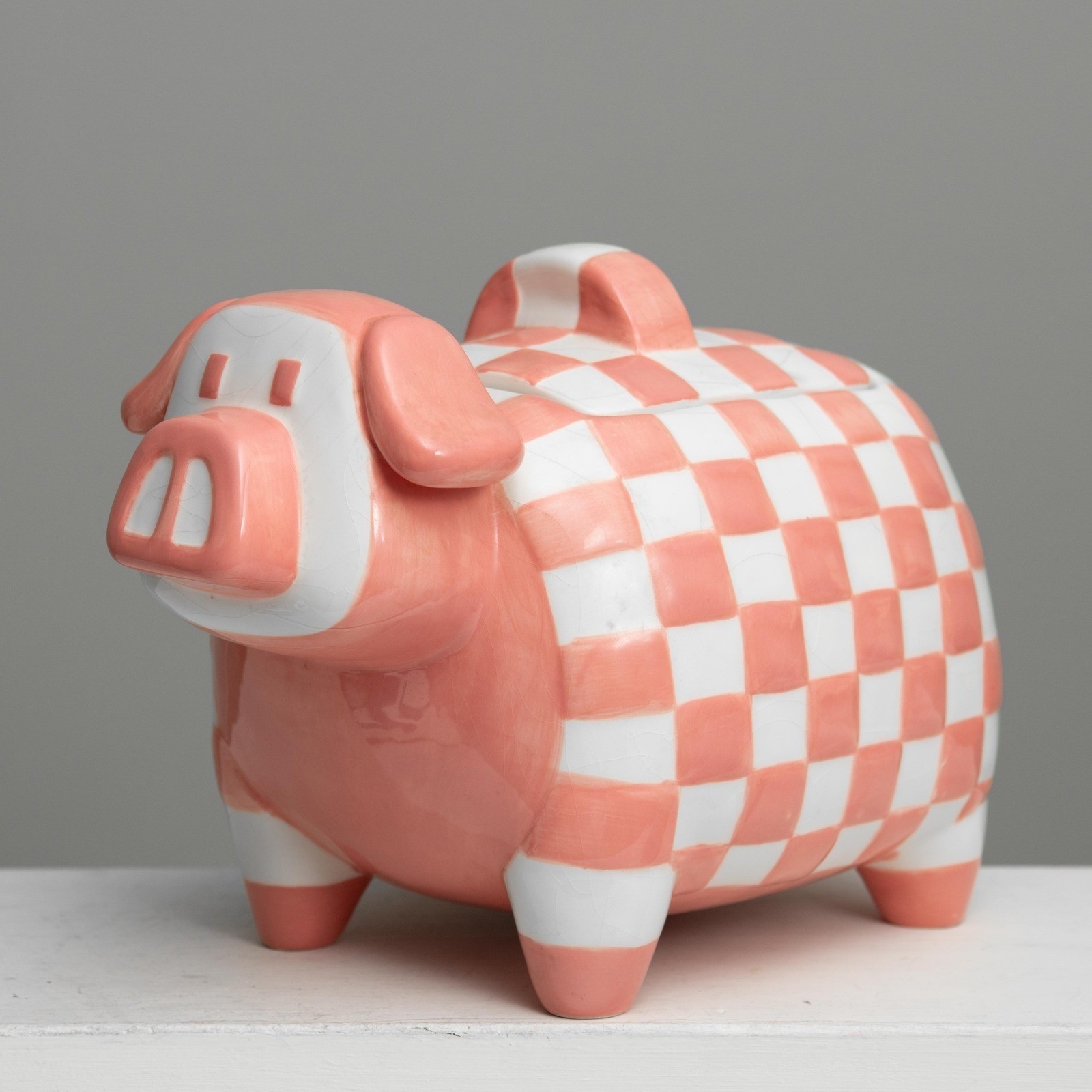 Pink and white checkered ceramic pig-shaped cookie jar.