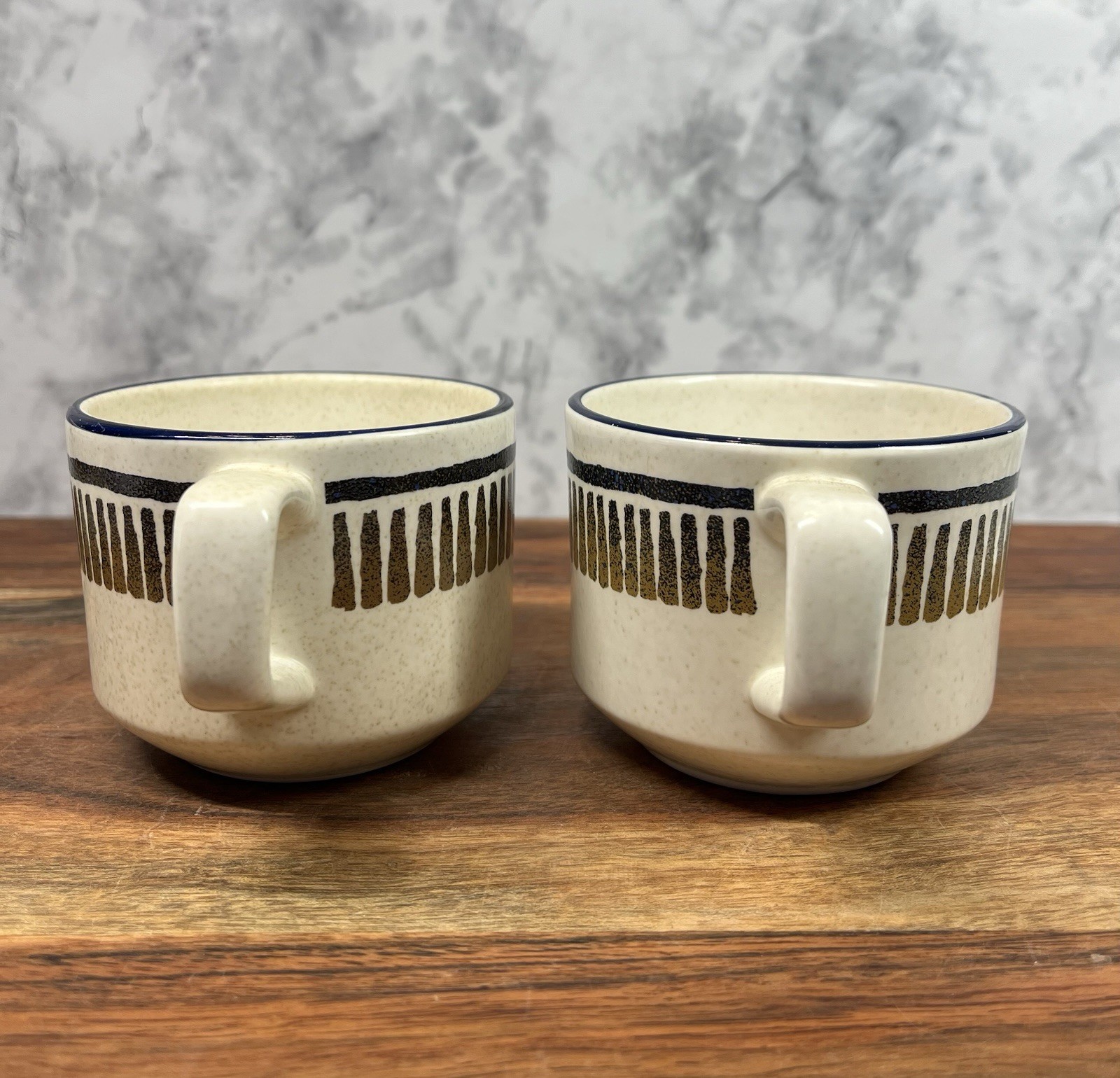 Two beige LENOX Temper Ware coffee mugs with black and gold horizontal stripes and navy rim bands, made in USA.