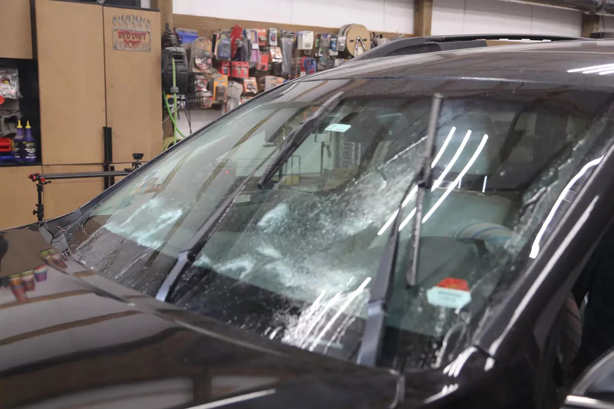 A vehicle spraying windshield fluid onto its windshield with the wipers moving.