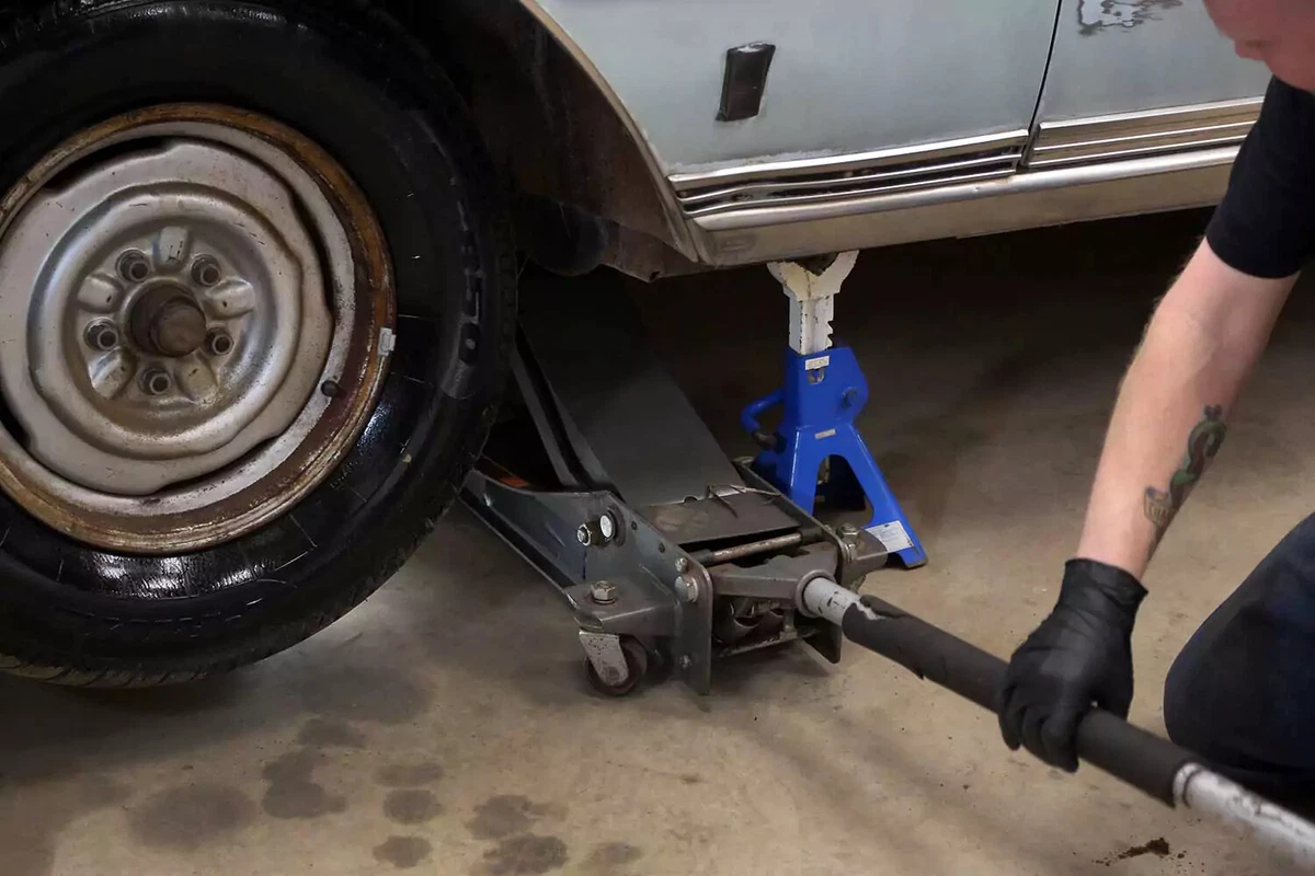 A vehicle raised with a floor jack and a jack stand.