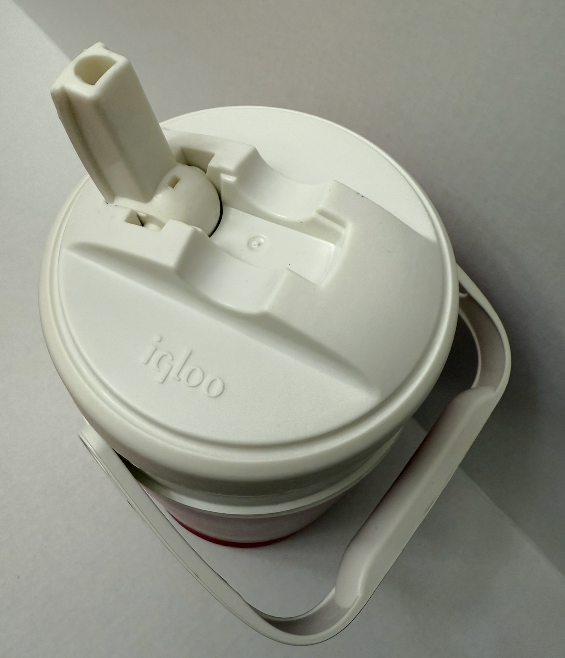 White vintage NWT Igloo 1/2 gallon cooler with black lid, side handle, and embossed logo on top.