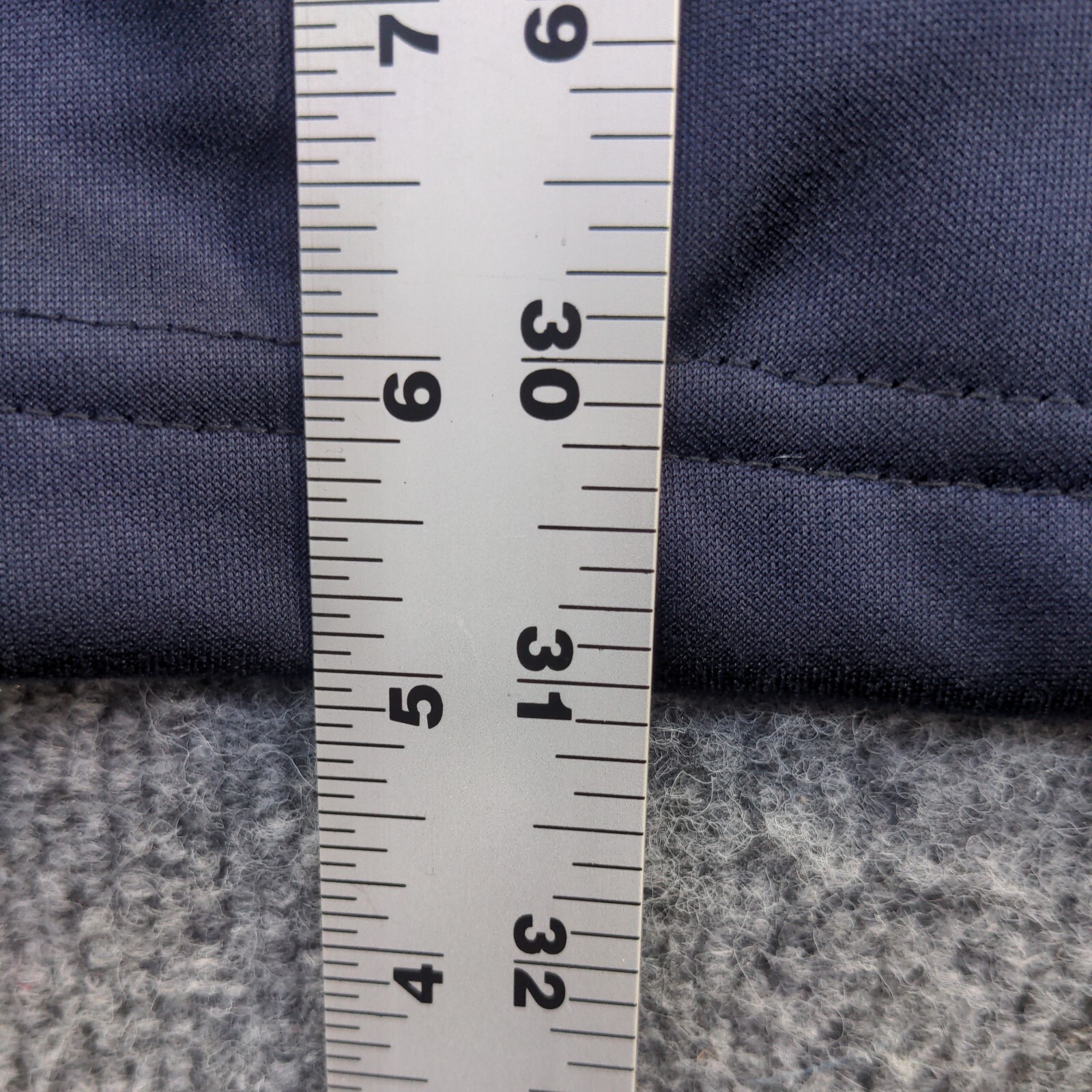 Blue full zip jacket with white stitching, 2XL size, shown against a gray fabric tape measure on a light wooden surface.