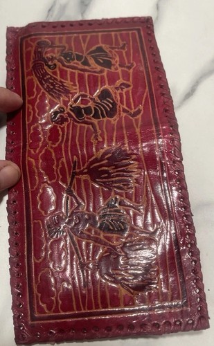 Red leather wallet with embossed ancient warrior and bird designs, tan border, and “USA Made” text on front.