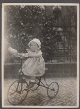 Little girl in knit bonnet on tricycle with bell snapshot ca 1920s
