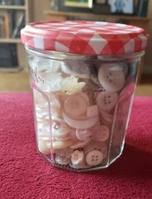 White buttons in a jam jar various shapes, sizes, and materials. 