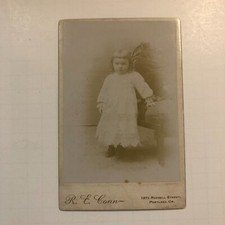 Little Girl White Dress Standing In Front of Chair - Cabinet Photo