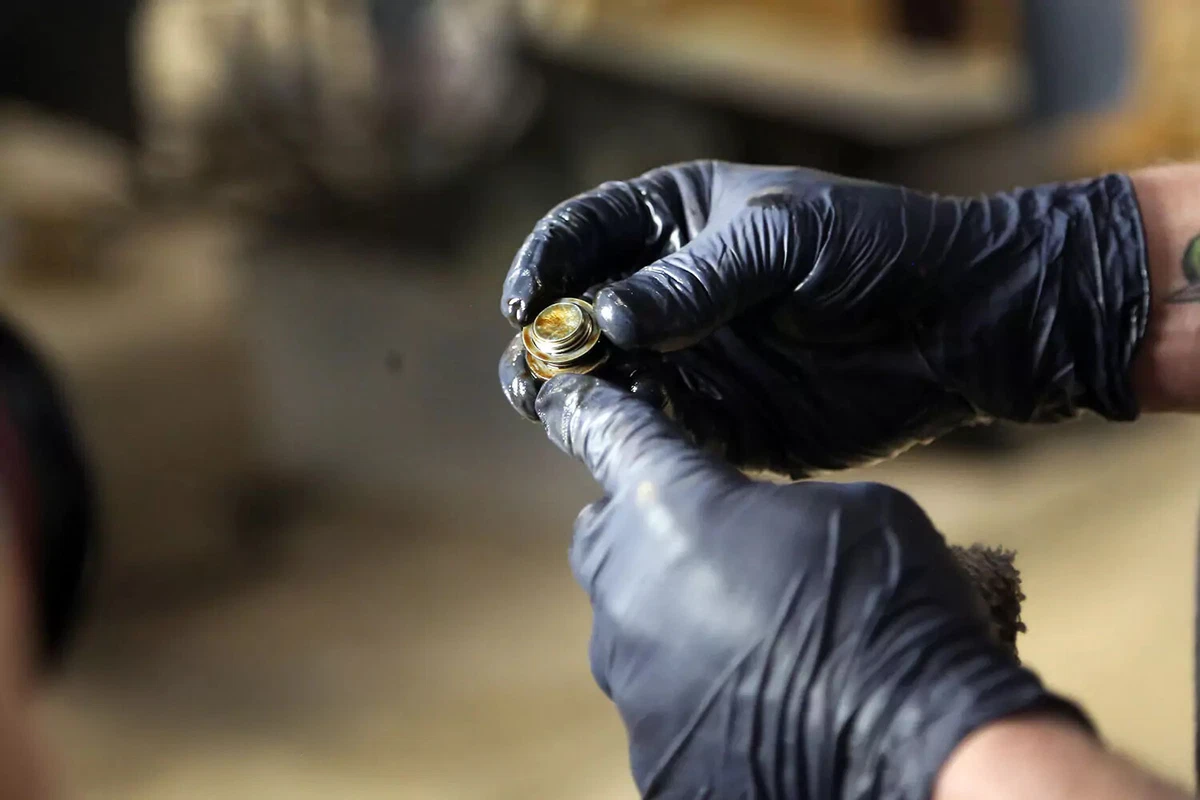 A mechanic inspects a used oil plug.