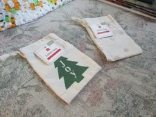 small fabric gift bags, one with green joy tree & the other gold snowflakes