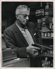 1963 Press Photo Sidney Scalise looks at pistol that he fired at bandits.