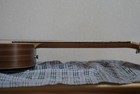 Brown wood fretboard of Taylor BT1e baby guitar with silver hardware, resting on a light gray plaid fabric surface.