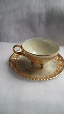 Vintage  tri-footed cup and a reticulated saucer gold in color and iridescent