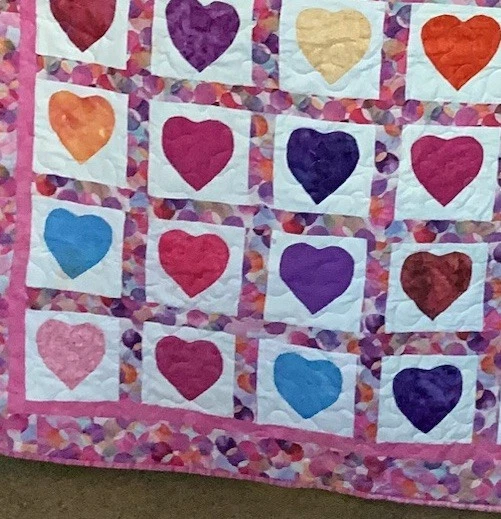 Corazones aplicados bordeados por una tela circular coordinada en un edredón hecho a mano Foto 3 de 4