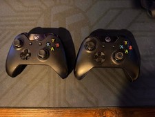 2x Black Xbox One Controllers with Nyko Recha...