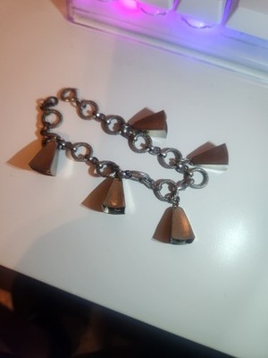 This is a silver-tone link charm bracelet W/ five bell-shaped charms attached.